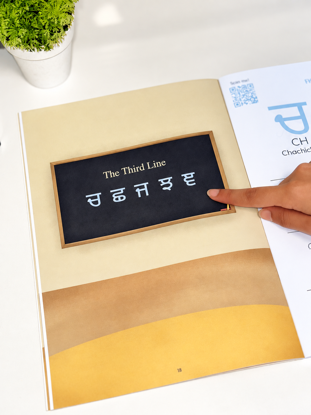 A close-up of an open book or booklet showing a page with a small blackboard-style panel reading 'The Third Line' in Gurmukhi script. A person's finger is touching the panel, and part of a printed chart or worksheet is visible on the right.